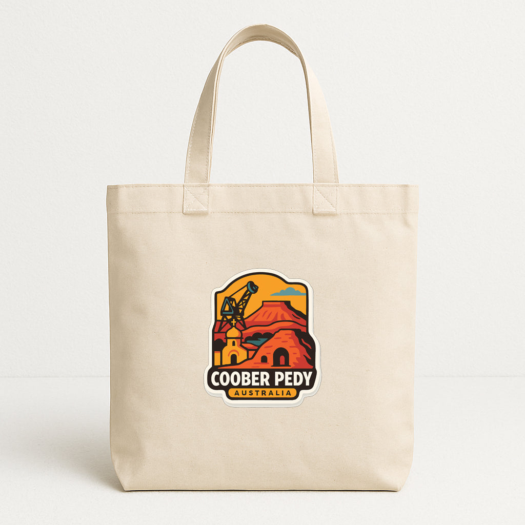 A beige tote bag with a colorful logo depicting a desert landscape and the text "COOBER PEDY AUSTRALIA".