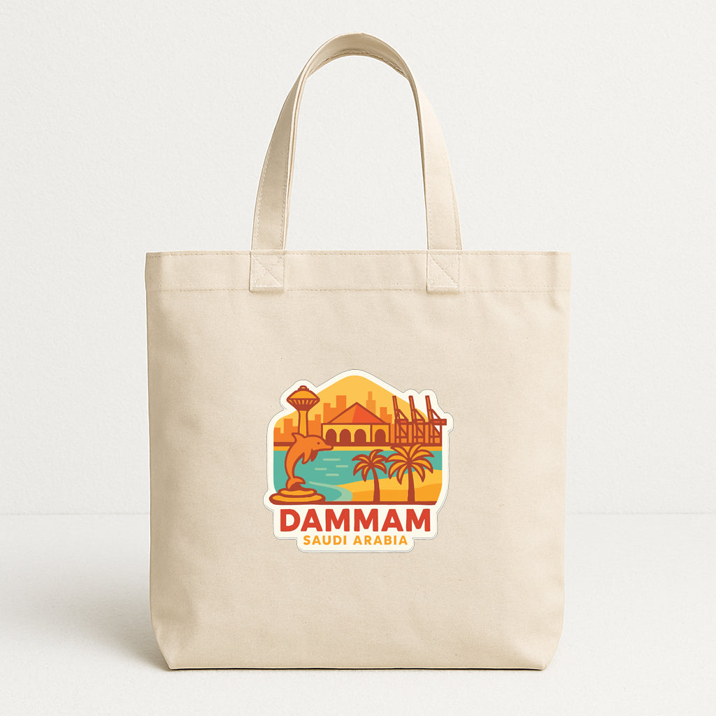 A beige tote bag with a printed design depicting a cityscape and palm trees, along with the text "DAMMAM SAUDI ARABIA".