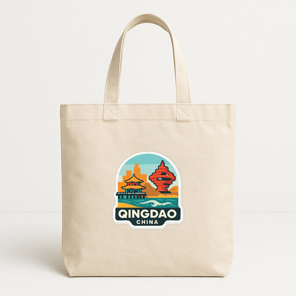 A beige tote bag with a sticker depicting a cityscape and the text "Qingdao China" printed on it.