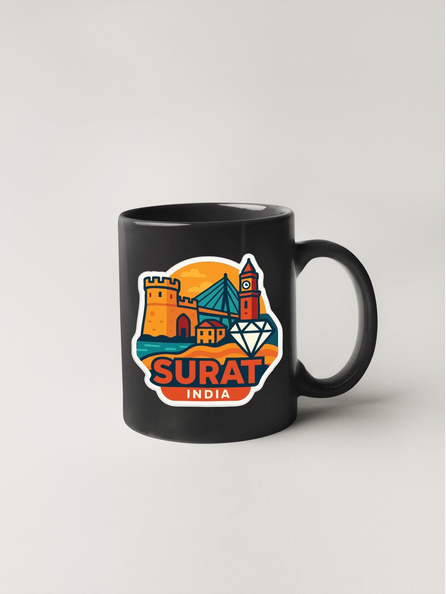 A black coffee mug with a colorful sticker depicting the city of Surat, India.