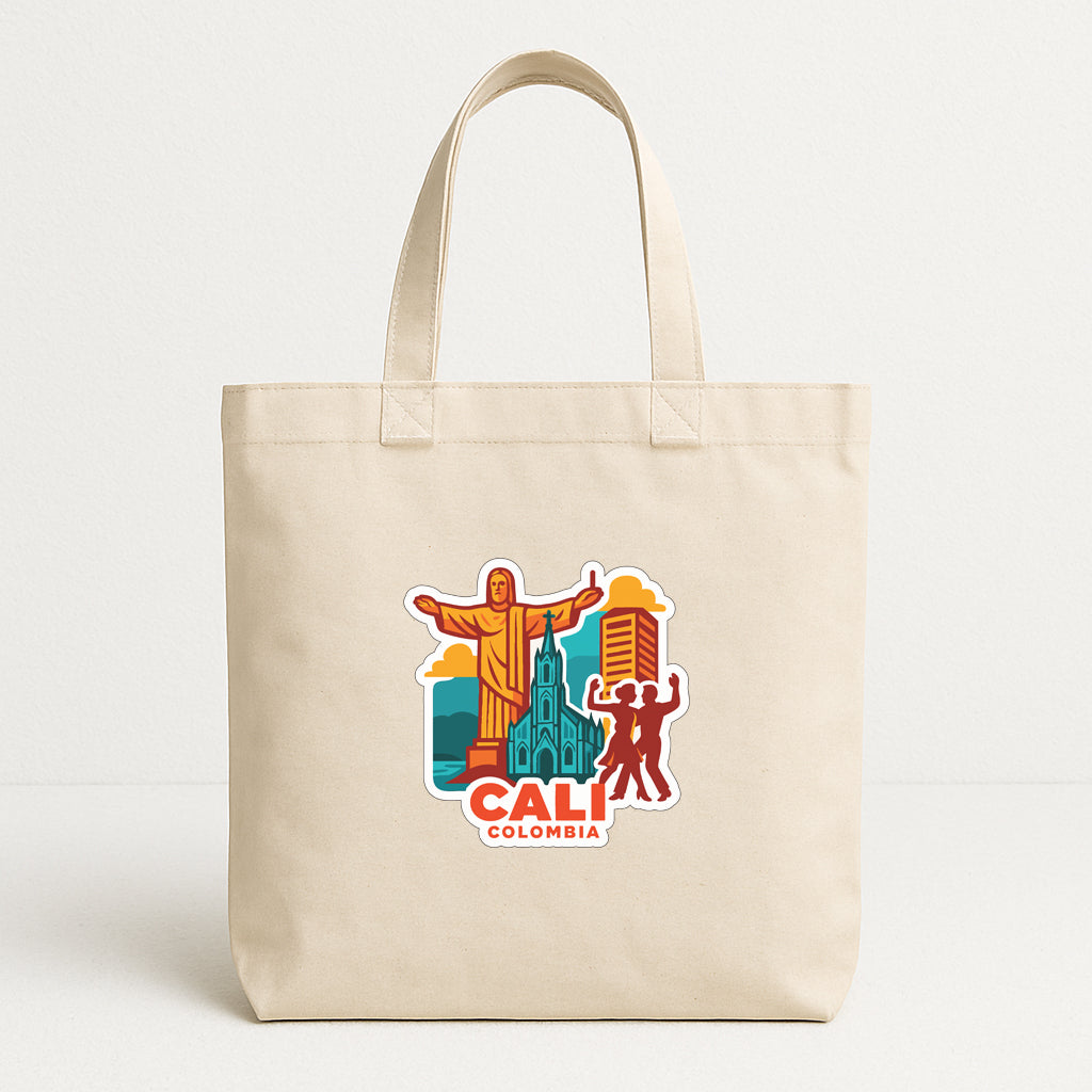 A beige tote bag with a colorful graphic depicting landmarks and people in Colombia, including the Christ the Redeemer statue, the Cathedral of Our Lady of Guadalupe, and a person in a red shirt.