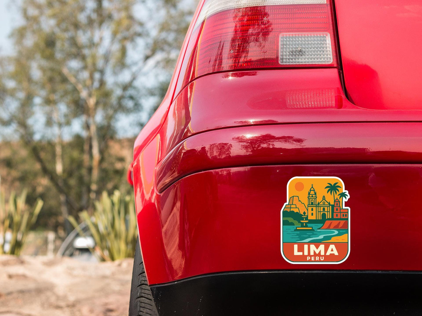 the rear end of a red car with a sticker on the trunk that features a colorful illustration of a cityscape and the word "LIMA" in the center.