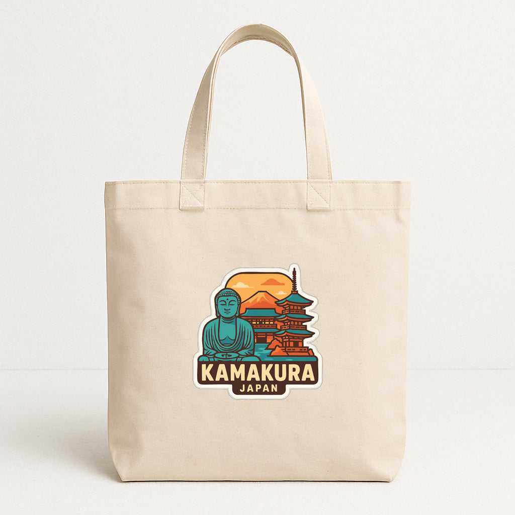 A beige tote bag with a sticker depicting a temple and Buddha statue, along with the text "KAMAKURA JAPAN".