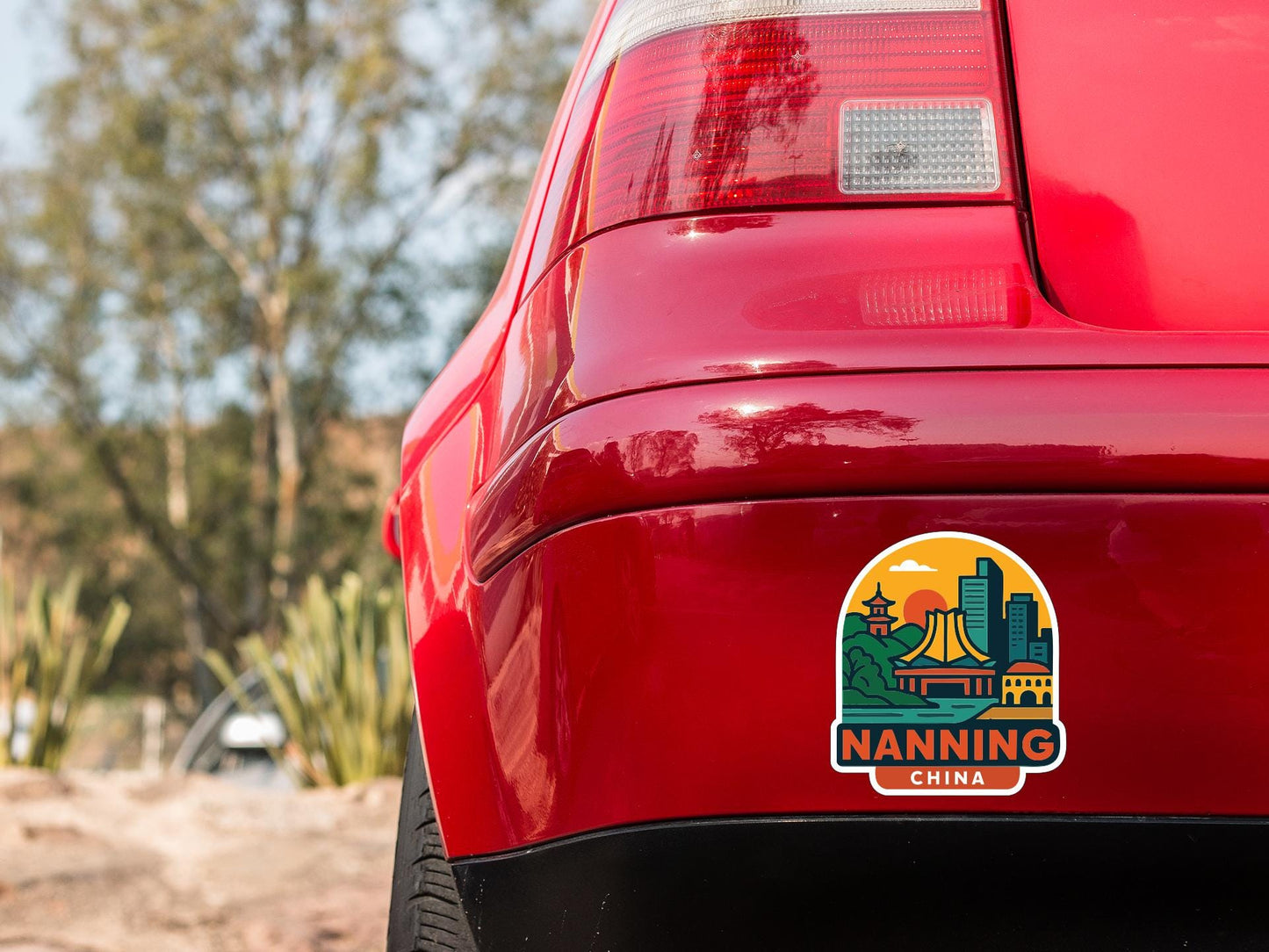 the rear end of a red car with a sticker on the trunk that says "NANNING CHINA".