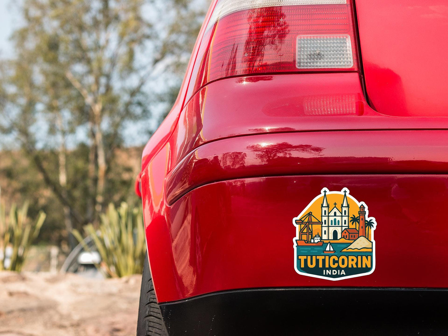 the rear end of a red car with a sticker on the trunk that says "TUTICORIN INDIA".