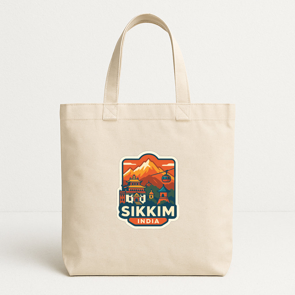 A beige tote bag with a colorful sticker depicting a mountain landscape and the text "Sikim India" printed on it.