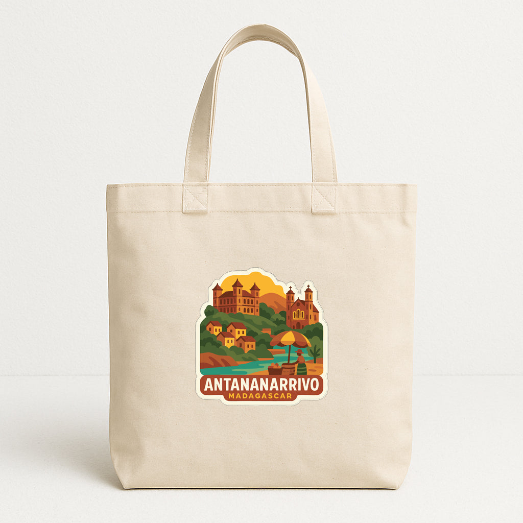 A beige tote bag with a printed design depicting a scenic landscape with buildings, a castle, and a body of water.