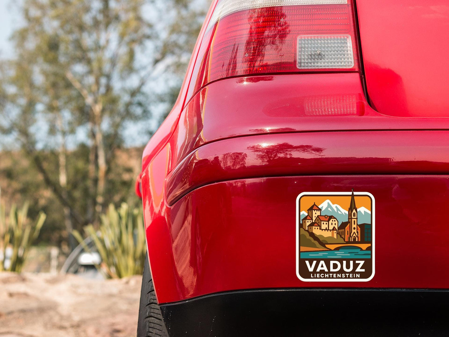 the rear end of a red car with a sticker on the trunk that says "VADUZ LIECHTENSTEIN".