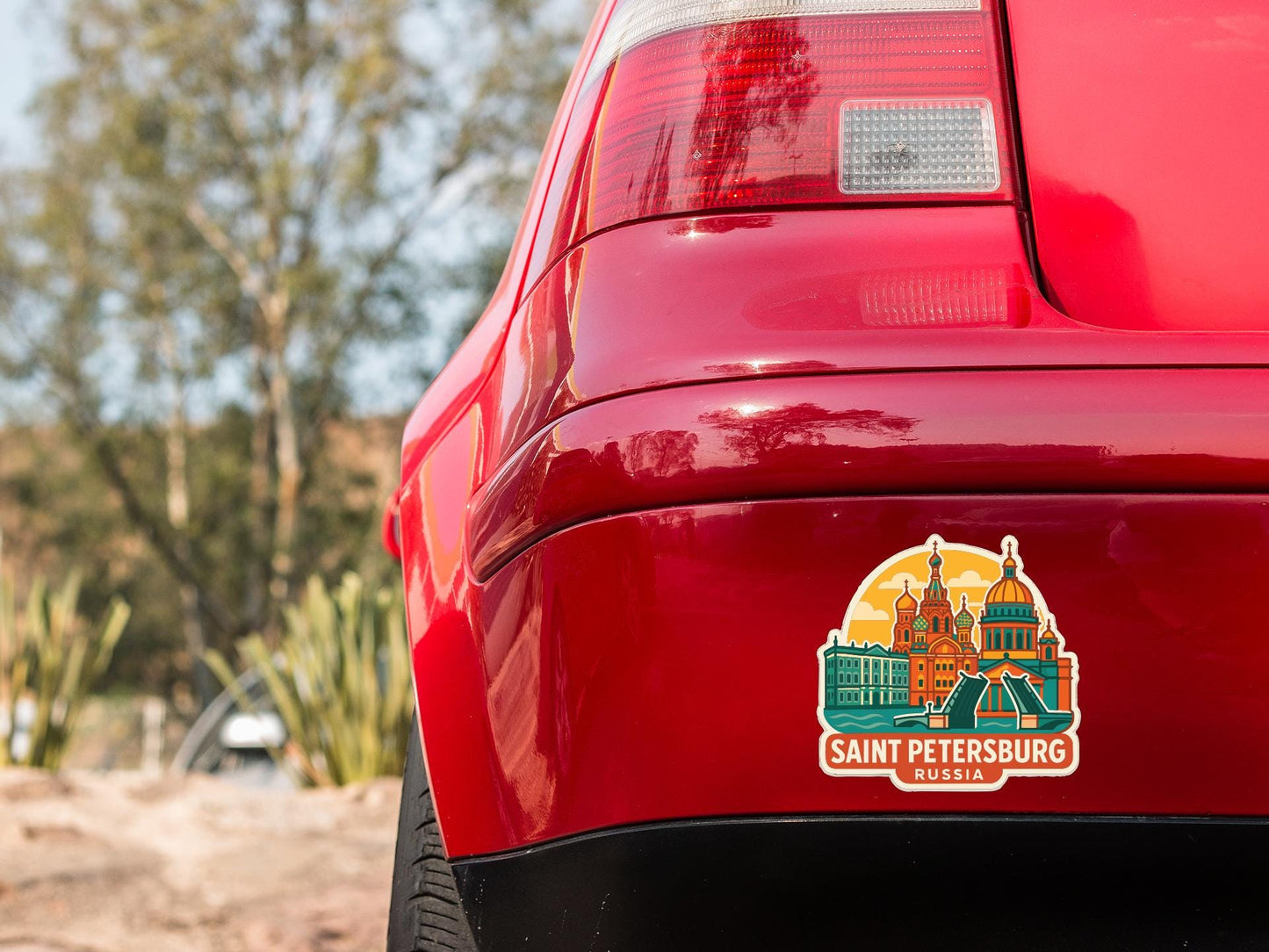 the rear end of a red car with a sticker on the trunk that features a cityscape and the text "SANT PETERSBURG RUSSIAN".
