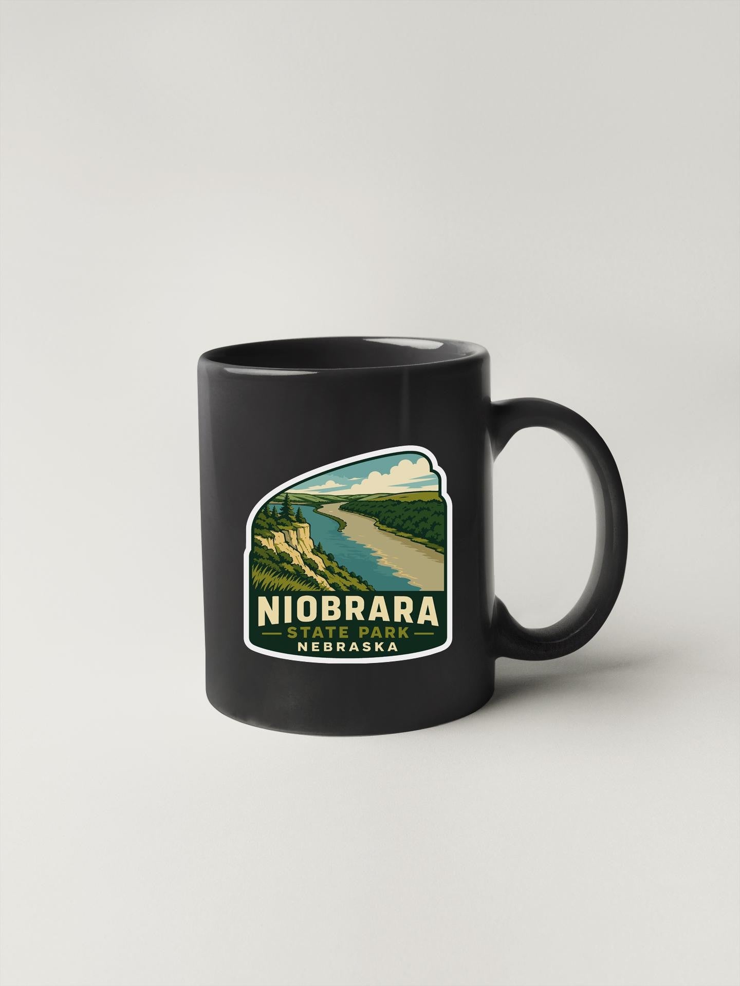 A black coffee mug with a sticker depicting Niobrara State Park in Nebraska.