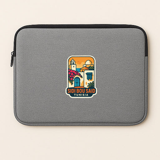 A gray laptop sleeve with a colorful sticker depicting a scenic view of Sidi Bou Said, Tunisia.