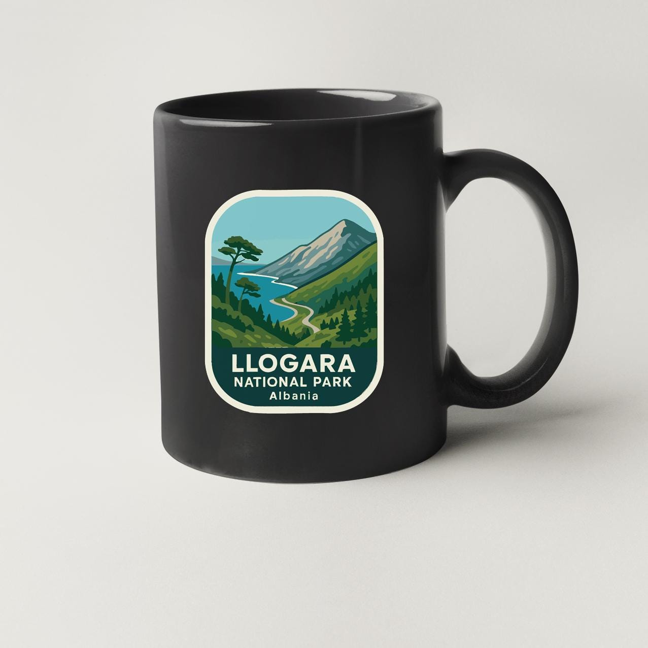 A black coffee mug with a label that says "LLOGGARA NATIONAL PARK ALBANIA".