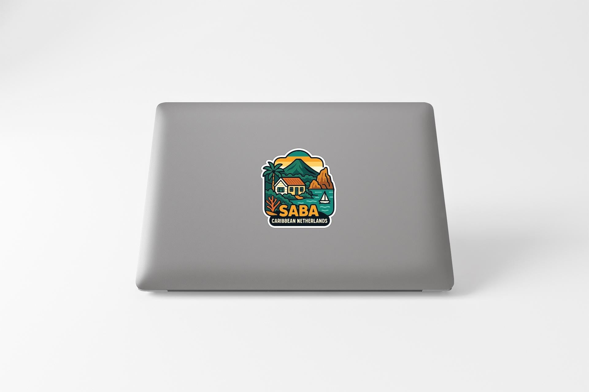 A sticker on the back of a laptop, depicting a tropical island scene with palm trees, a house, and mountains.