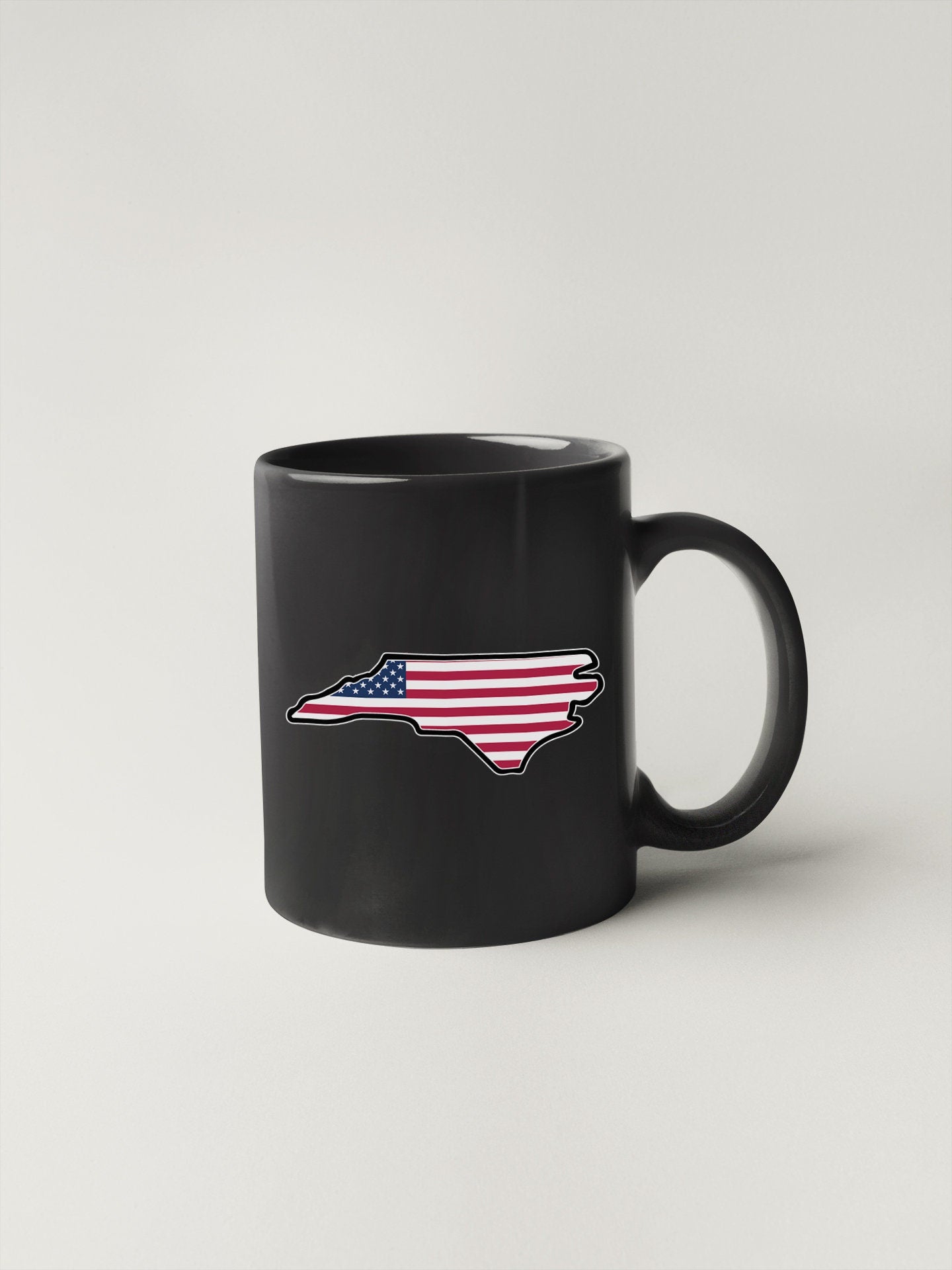a black coffee mug with a flag in the shape of a state