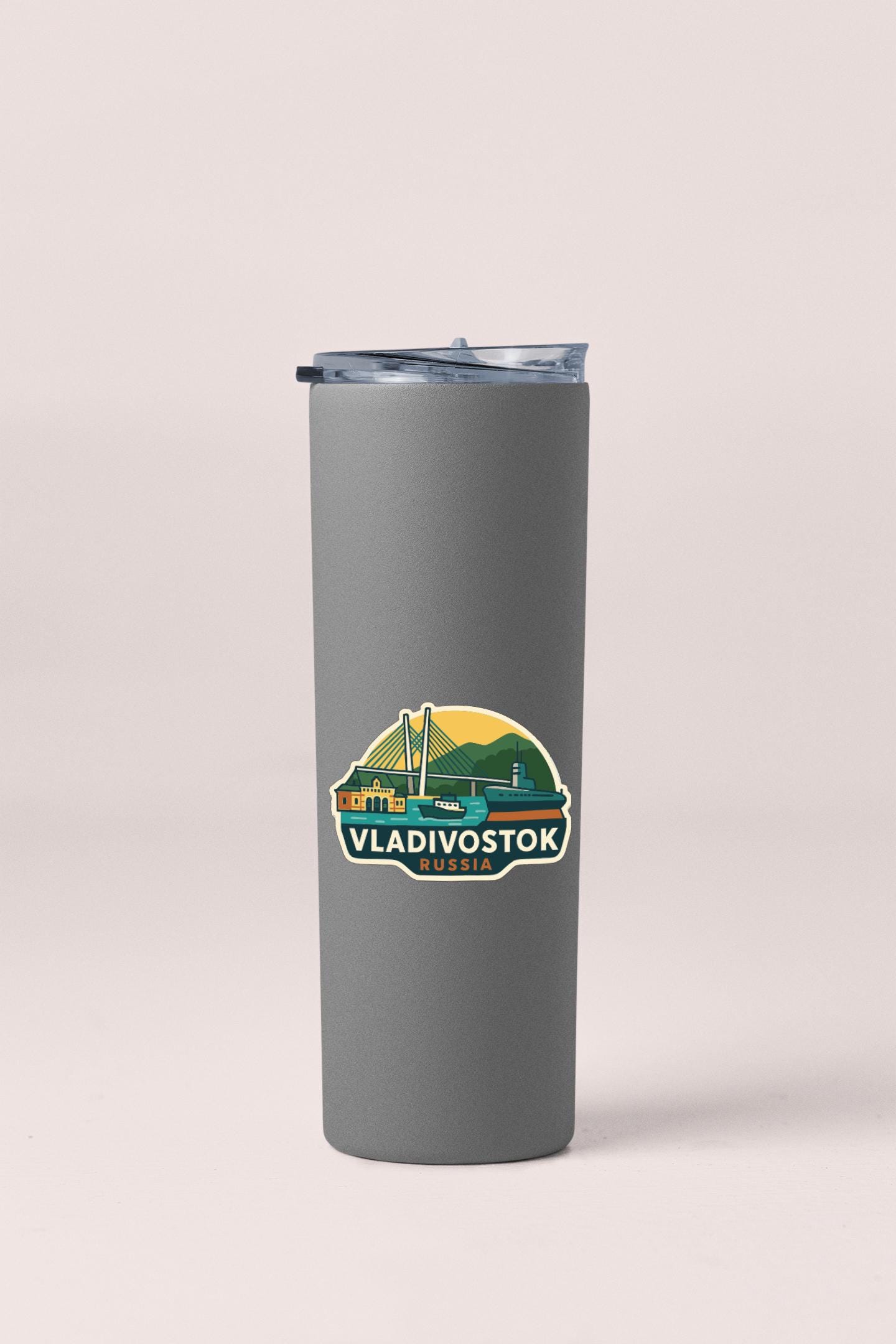 A gray insulated tumbler with a sticker depicting the Vladiivostok Bridge in Russia.