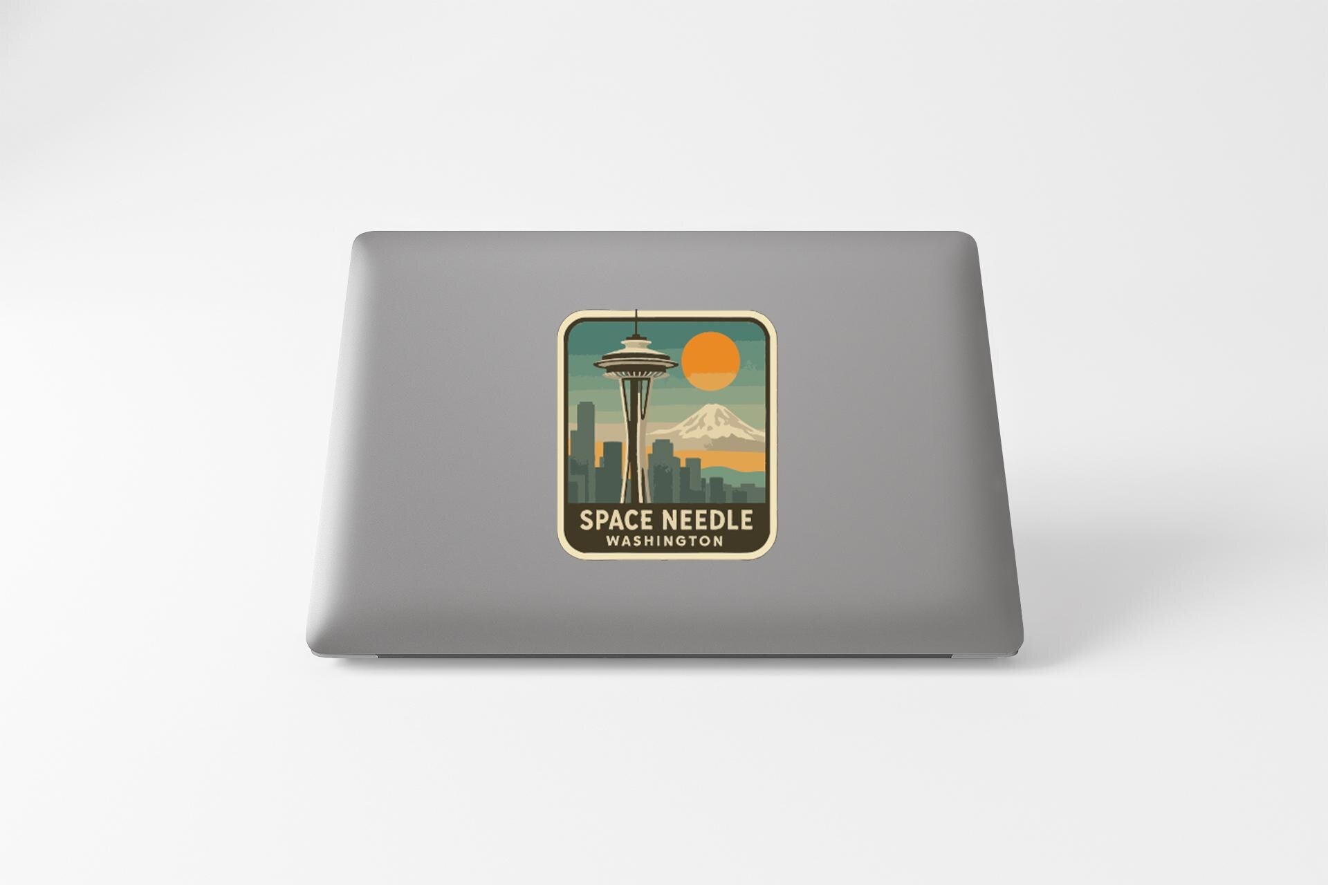 a sticker with a graphic of Space Needle and a mountain, along with the text "Space Needle Washington".