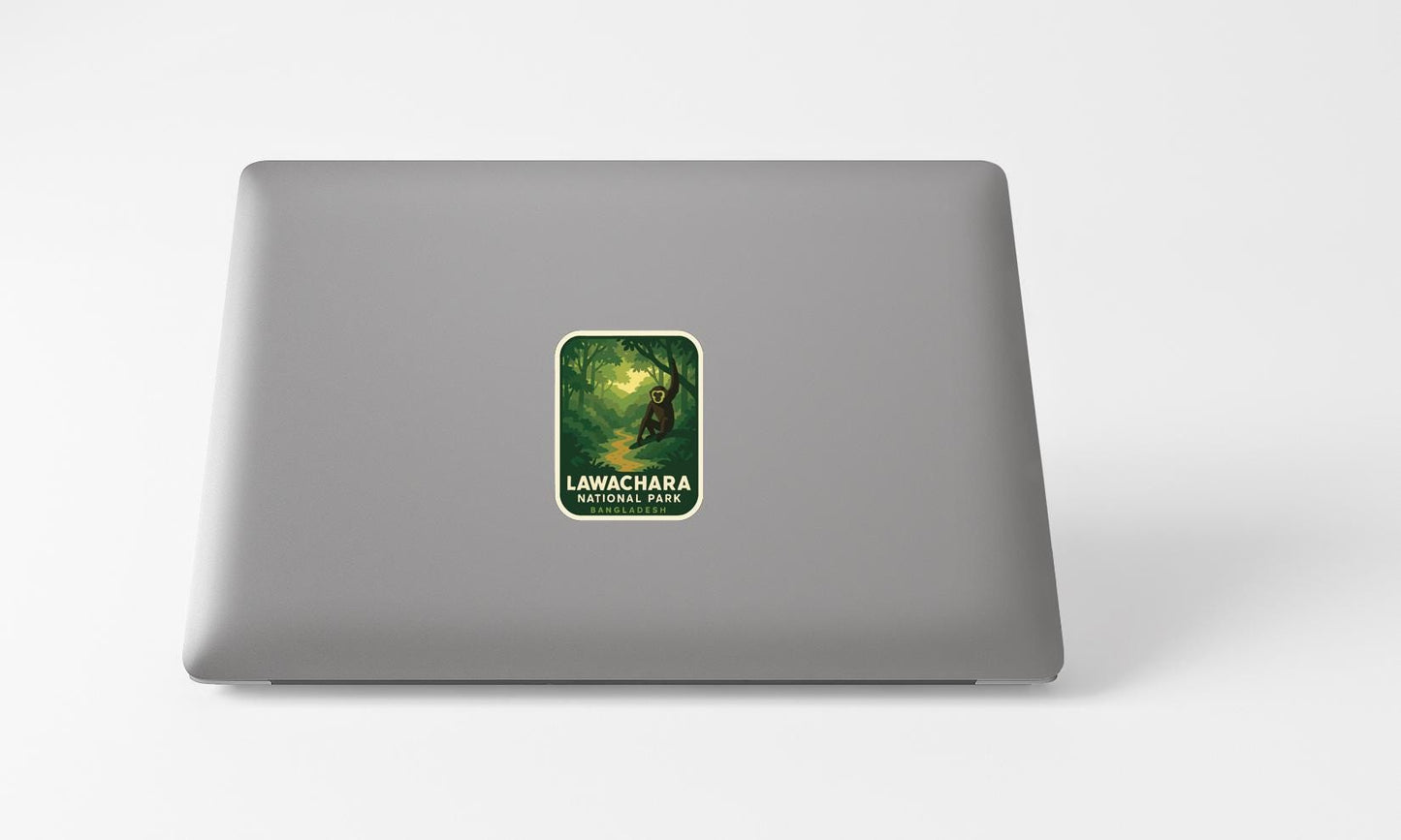 A sticker with a forest scene and text on a grey laptop.