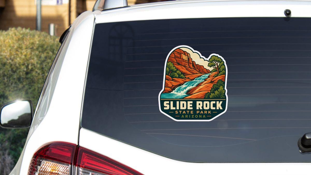 A sticker on the rear window of a white car, depicting a scenic landscape with a waterfall and mountains.