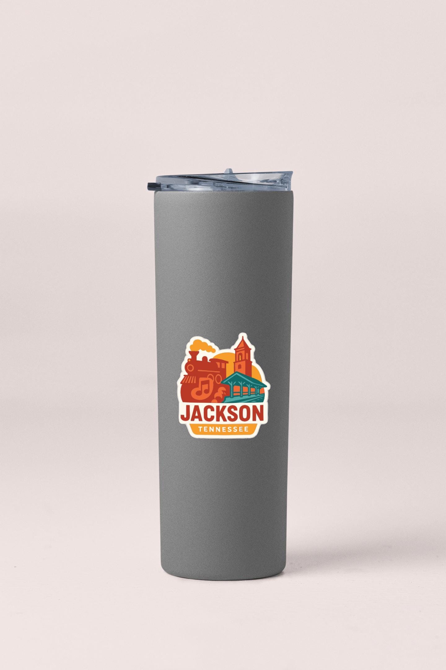 A gray insulated tumbler with a printed sticker depicting a cityscape and the text "JACKSON TENNESSEE" printed on it.