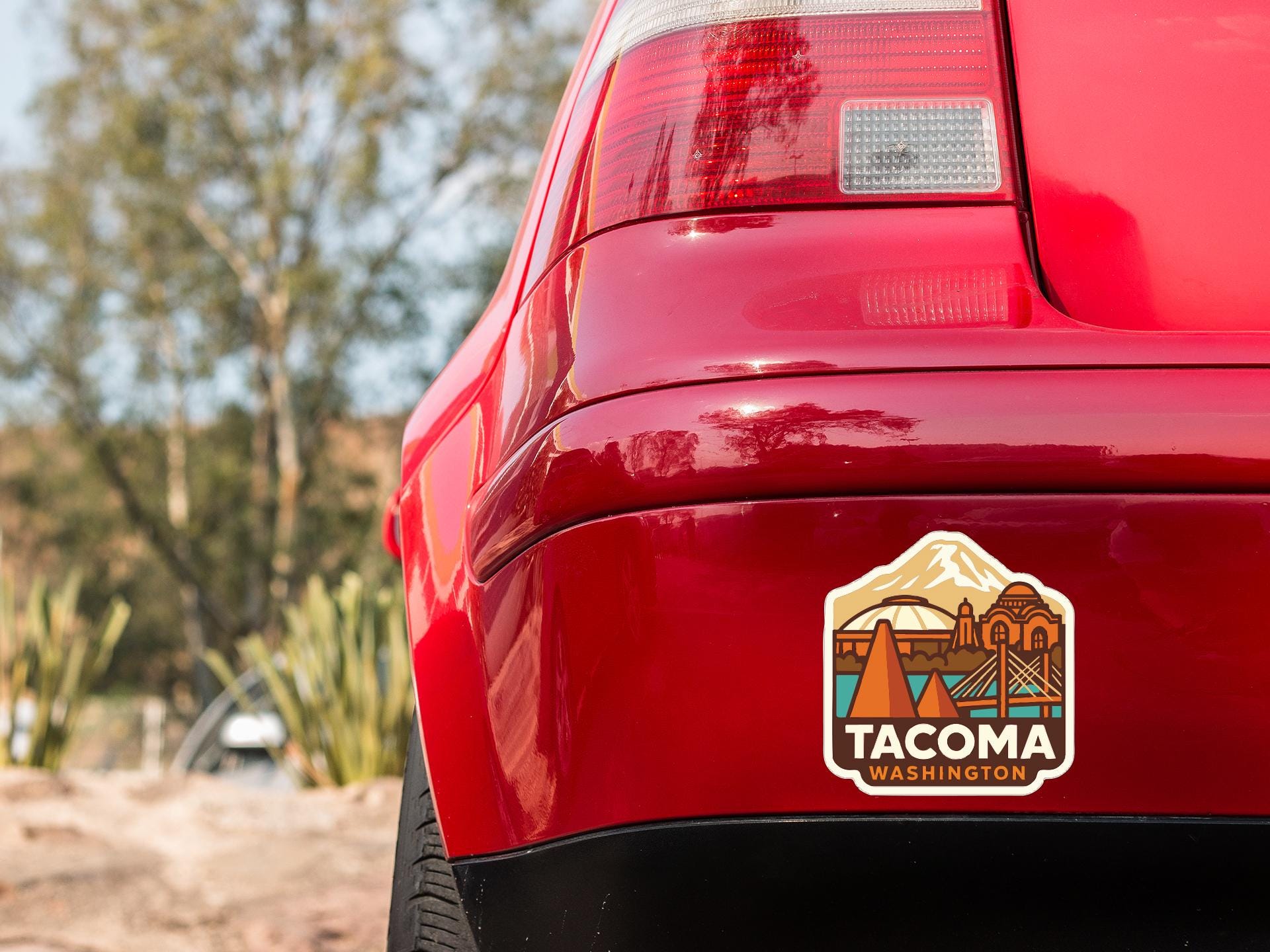 the rear end of a red car with a sticker on the back window that says "TACOMA WASHINGTON".