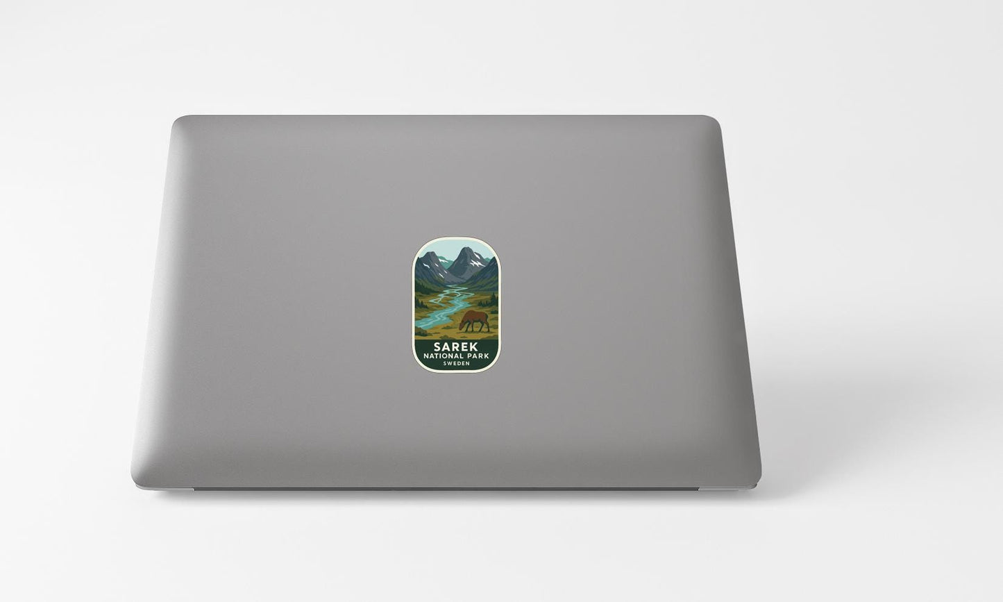 A sticker with a mountain landscape and a bear on it is placed on the back of a laptop computer.