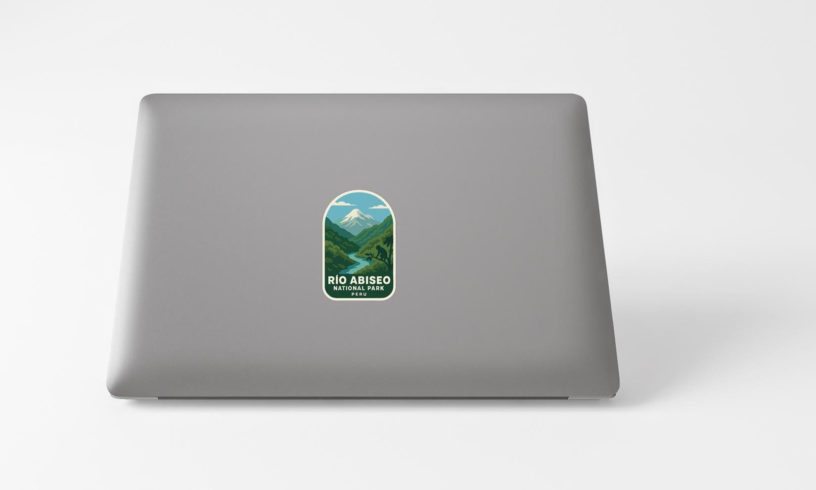 A sticker with a mountain landscape and the text "Rio Abisio National Park" printed on a grey laptop.