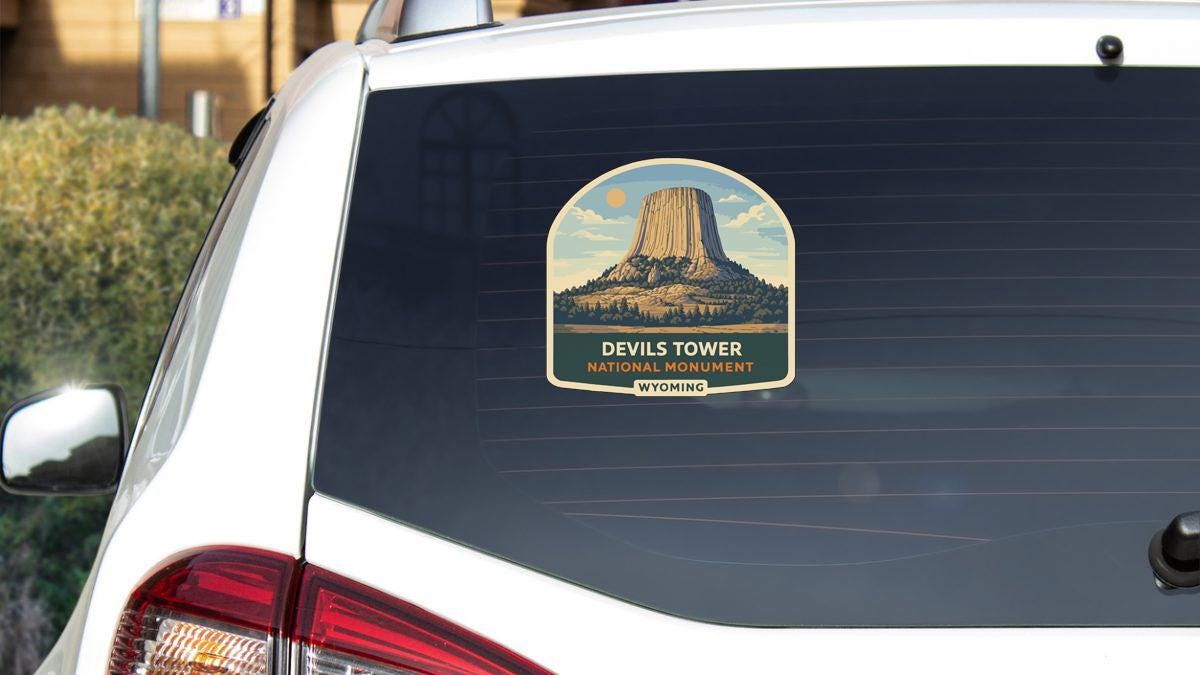 A sticker on the rear window of a car depicting the Devils Tower, a famous national monument in Yellowstone National Park.