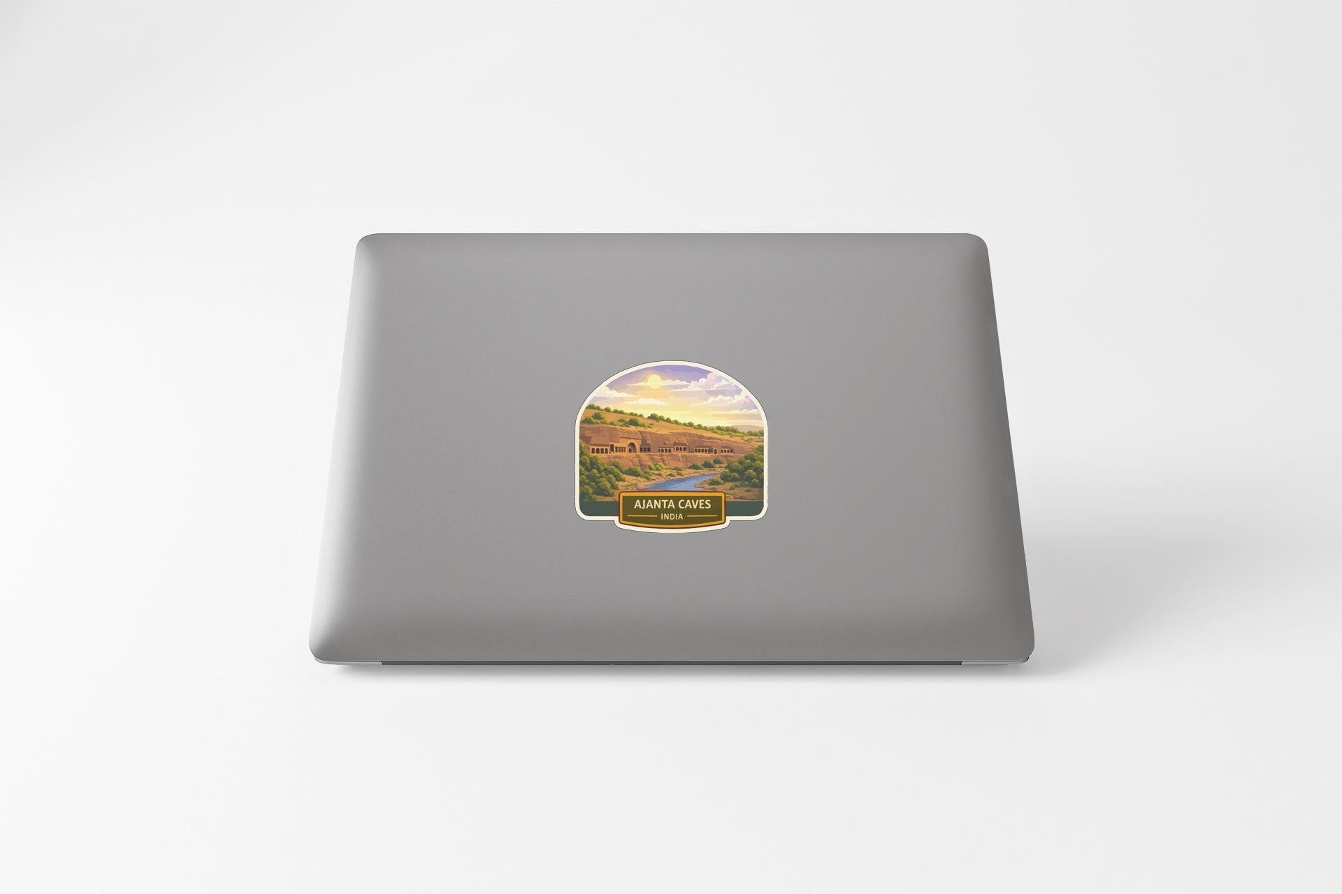 a sticker on the back of a laptop, depicting a scenic landscape with mountains and a river.