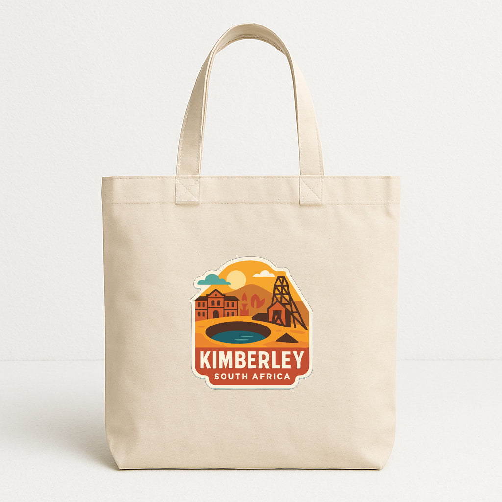 A beige tote bag with a printed design depicting a scenic landscape with buildings, a lake, and a sunset.