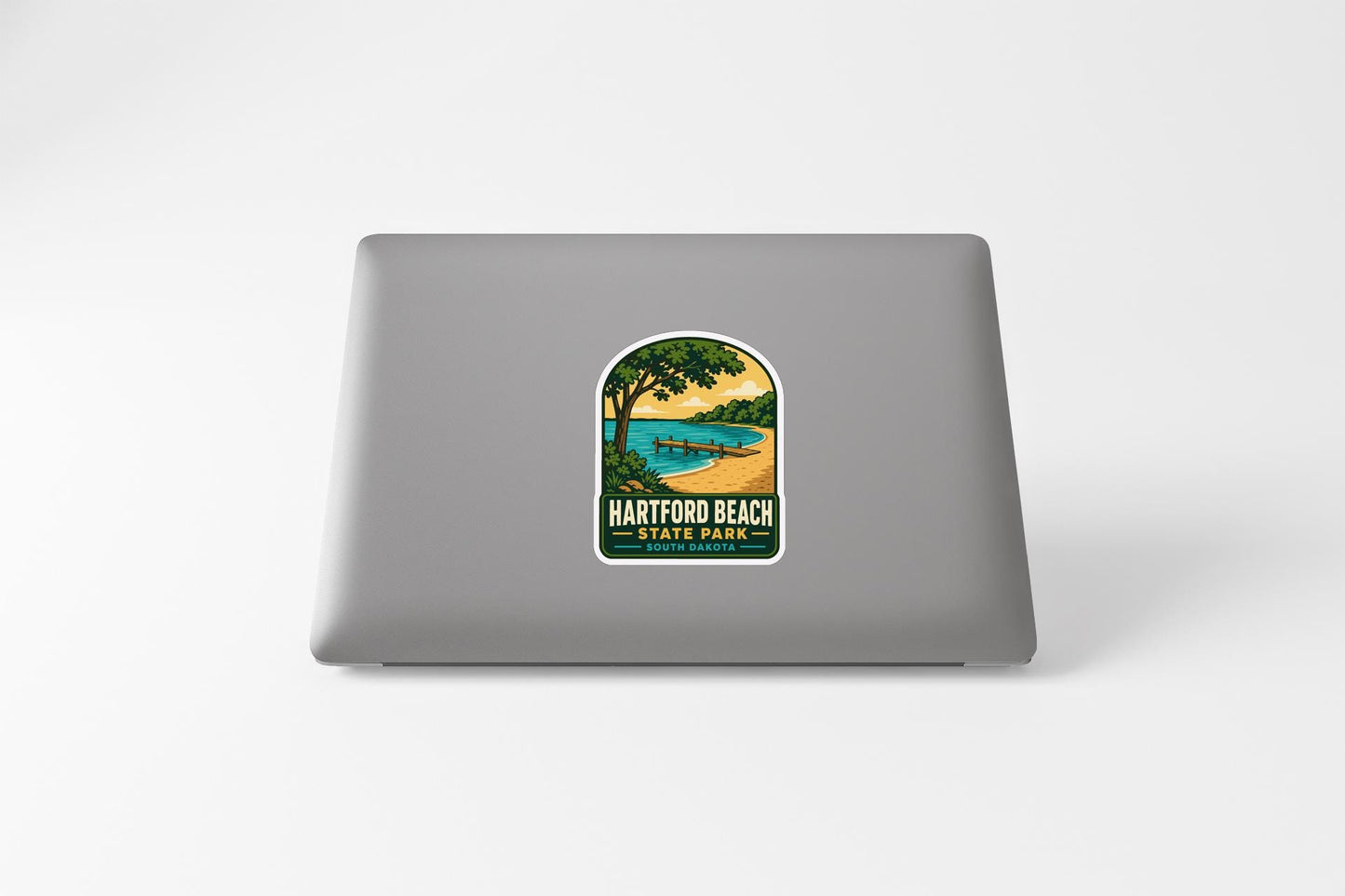 A sticker on the back of a laptop, depicting a scenic landscape with a beach, trees, and a body of water.