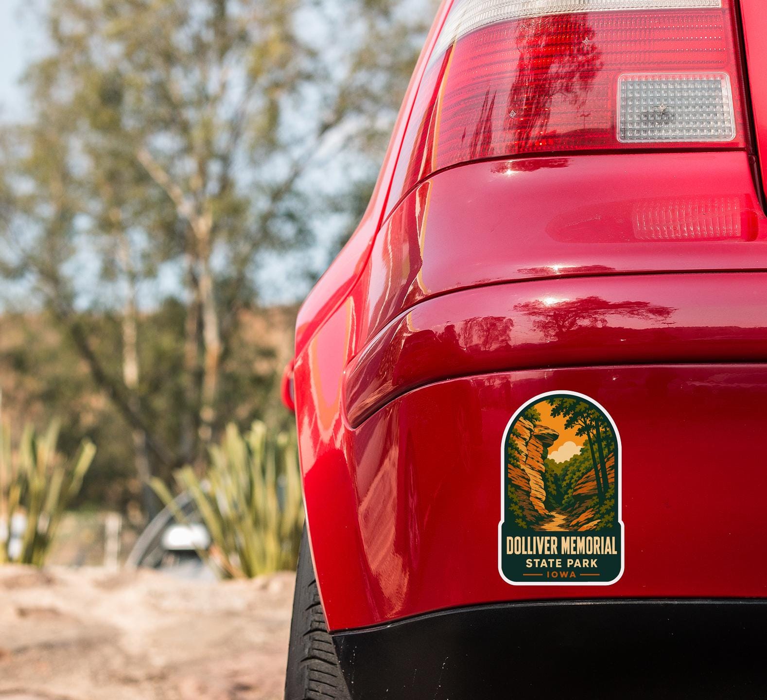 the rear end of a red car with a sticker on the trunk that reads "Dolliver Memorial State Park".
