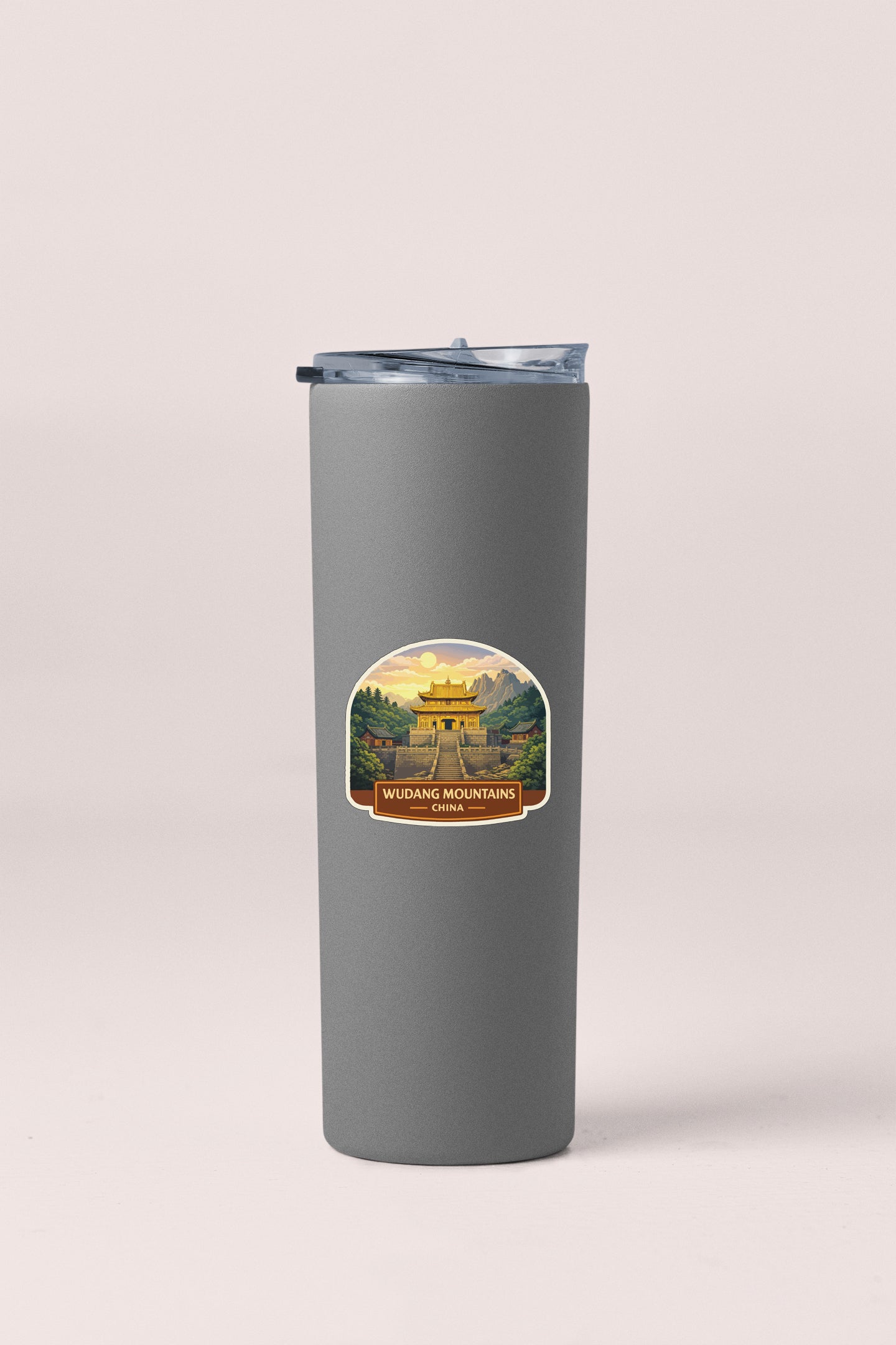 A gray tumbler with a sticker depicting a scenic mountain landscape.