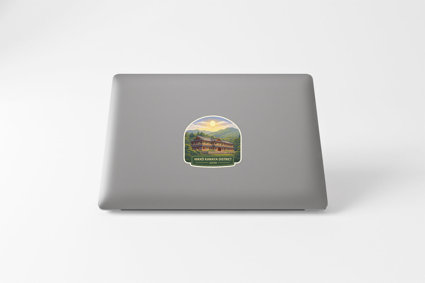 a sticker on the back of a laptop, depicting a scenic landscape with a building in the background.