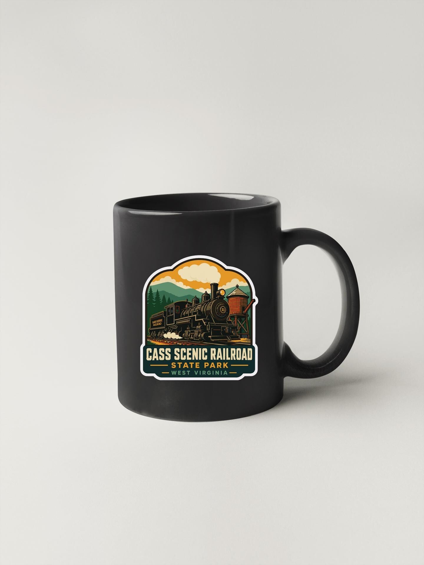 A black coffee mug with a colorful graphic depicting a train and mountains, along with the text "CASS SCENIC RAILROAD STATE PARK WEST VIRGINIA".