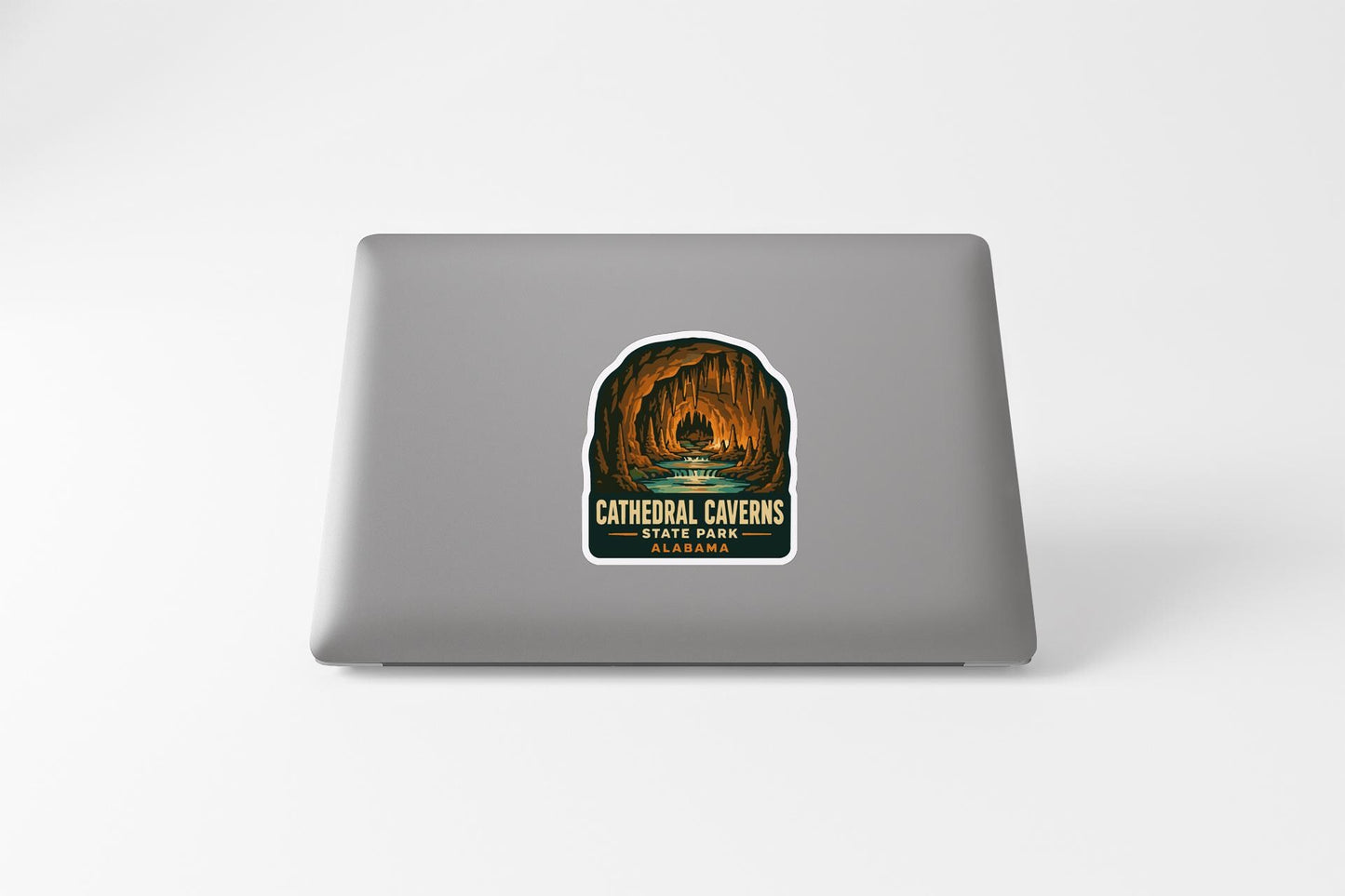 A sticker on the back of a laptop, depicting a cave with a waterfall and the text "Cathedral Caves SAN FRANCISCO PARK".