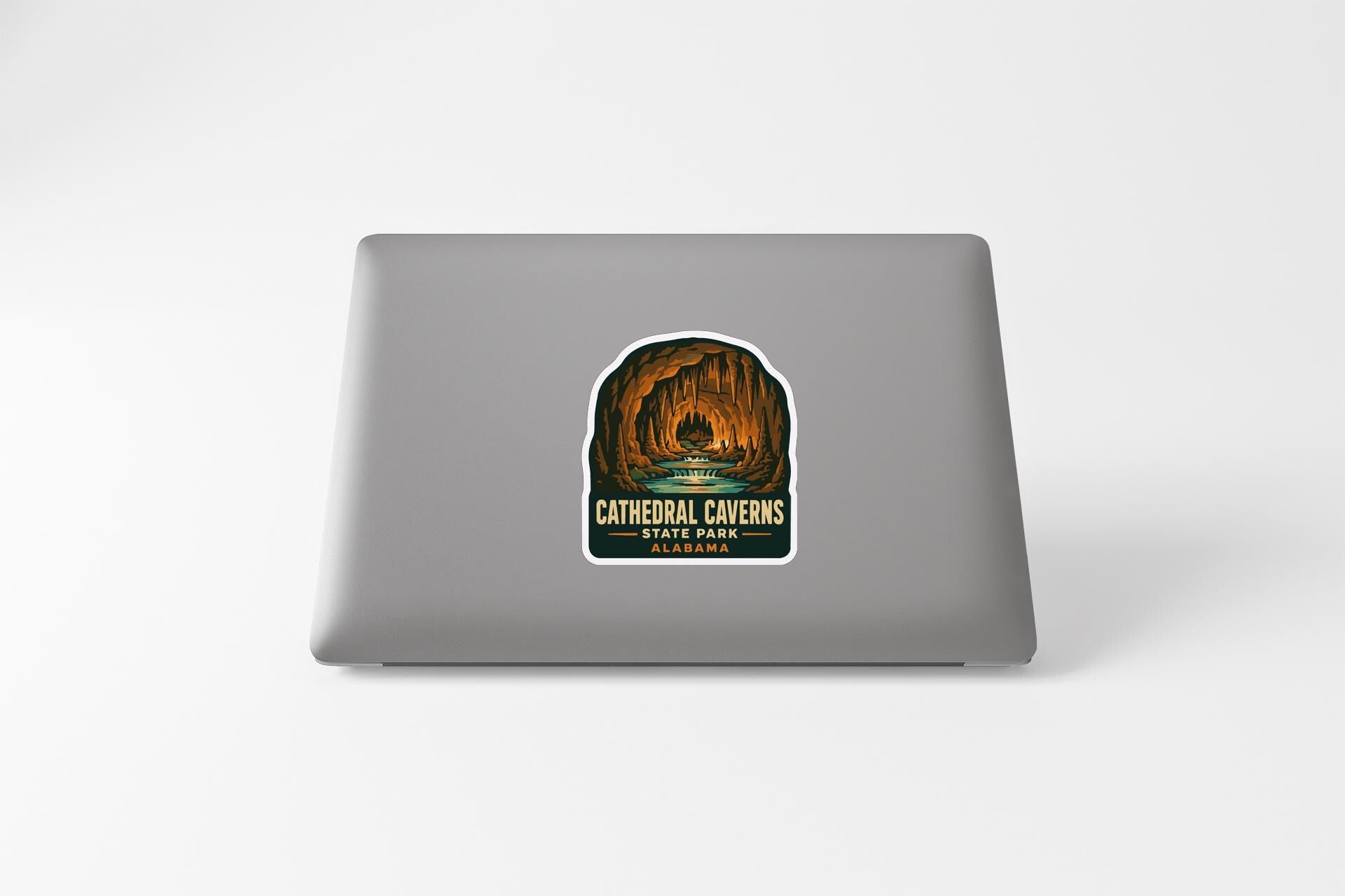 A sticker on the back of a laptop, depicting a cave with a waterfall and the text "Cathedral Caves SAN FRANCISCO PARK".
