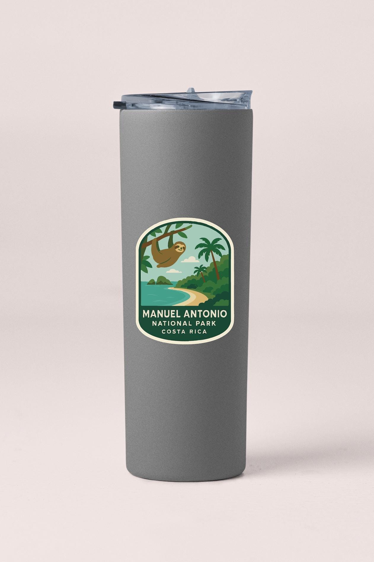 A gray tumbler with a label that features a sloth hanging from a tree and a tropical landscape.
