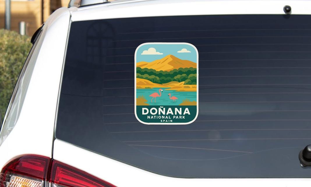 A sticker on the rear window of a car, depicting a scenic landscape with mountains, a lake, and flamingos.