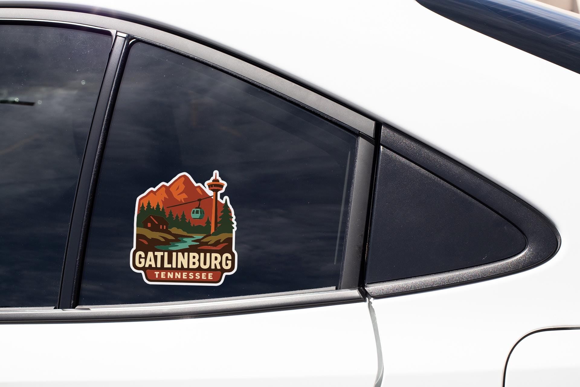 A sticker on the side of a car window, depicting a scenic mountain landscape with a building and a cable car.