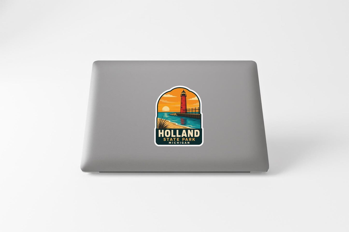 A sticker on the back of a laptop, depicting a lighthouse and a sunset over a body of water, with the text "Holland State Park" below it.