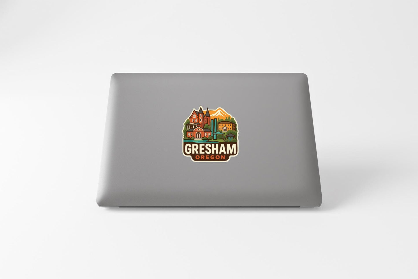 a sticker with a graphic of a city and the text "Gresham Oregon" on the back of a laptop.