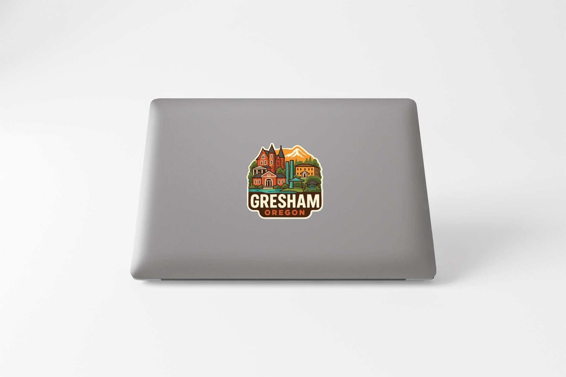 a sticker with a graphic of a city and the text "Gresham Oregon" on the back of a laptop.