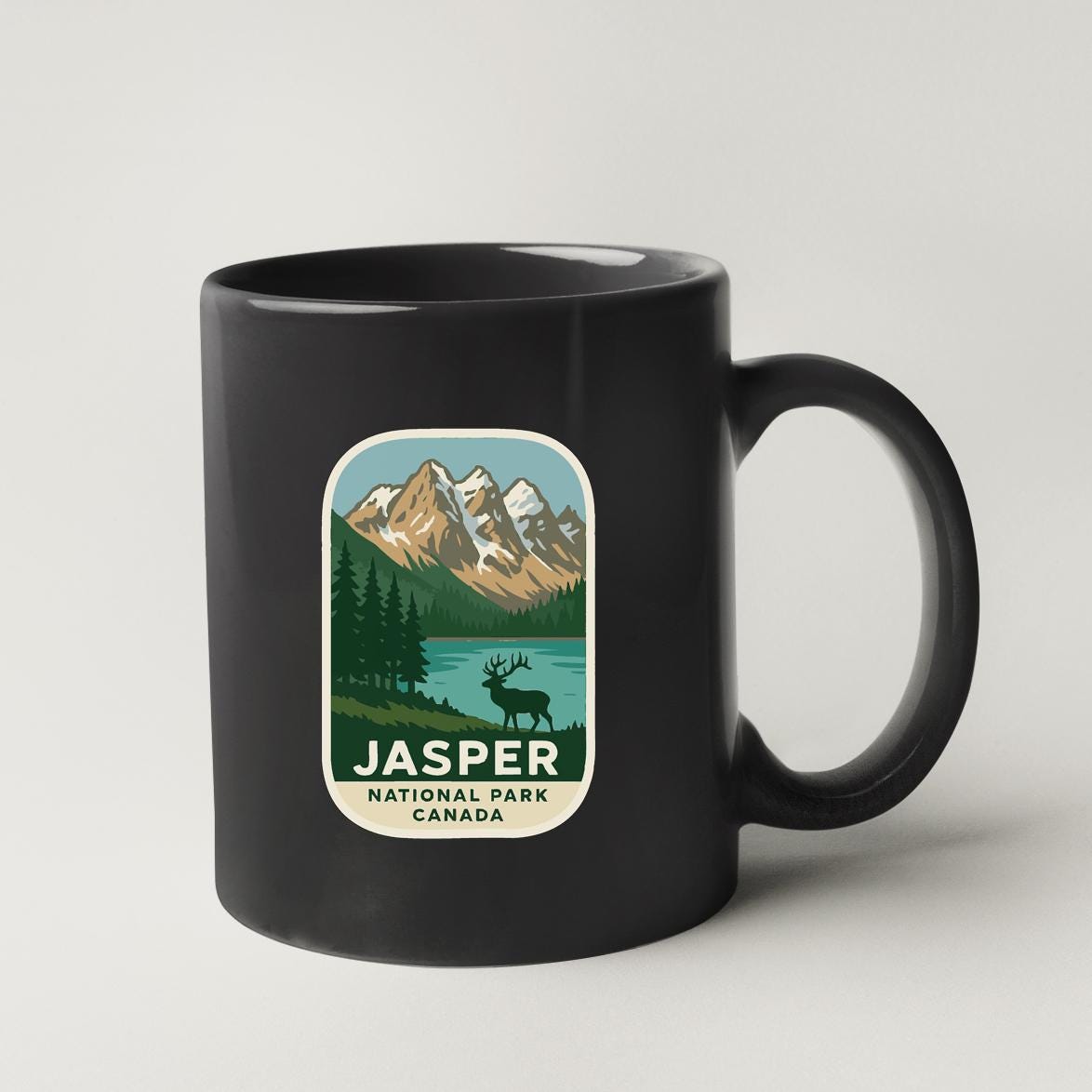 A black coffee mug with a label that features a mountain landscape and a moose, along with the text "JASPER NATIONAL PARK CANADA".