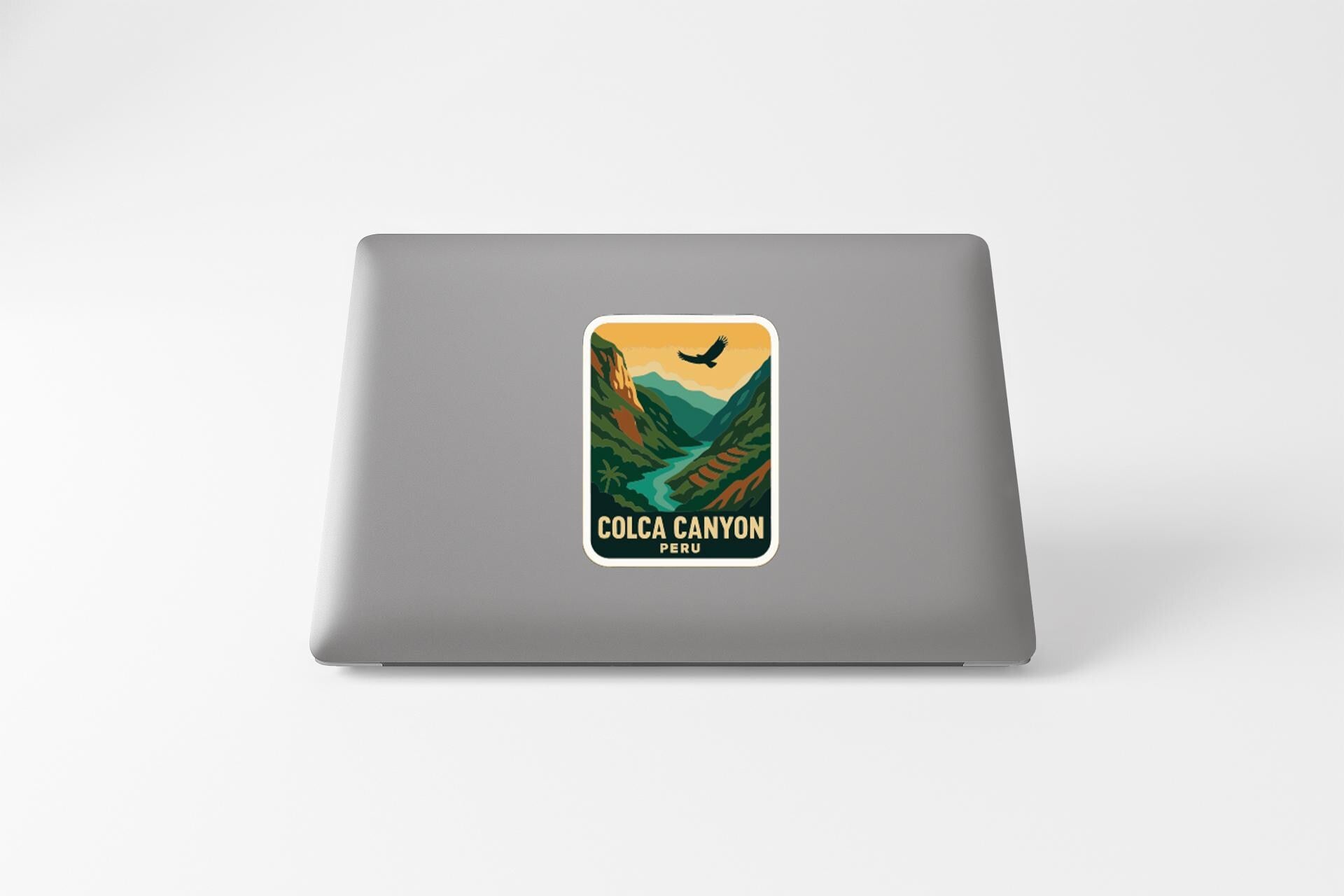 A sticker on the back of a laptop, depicting a scenic mountain landscape with a bird flying over the mountains.