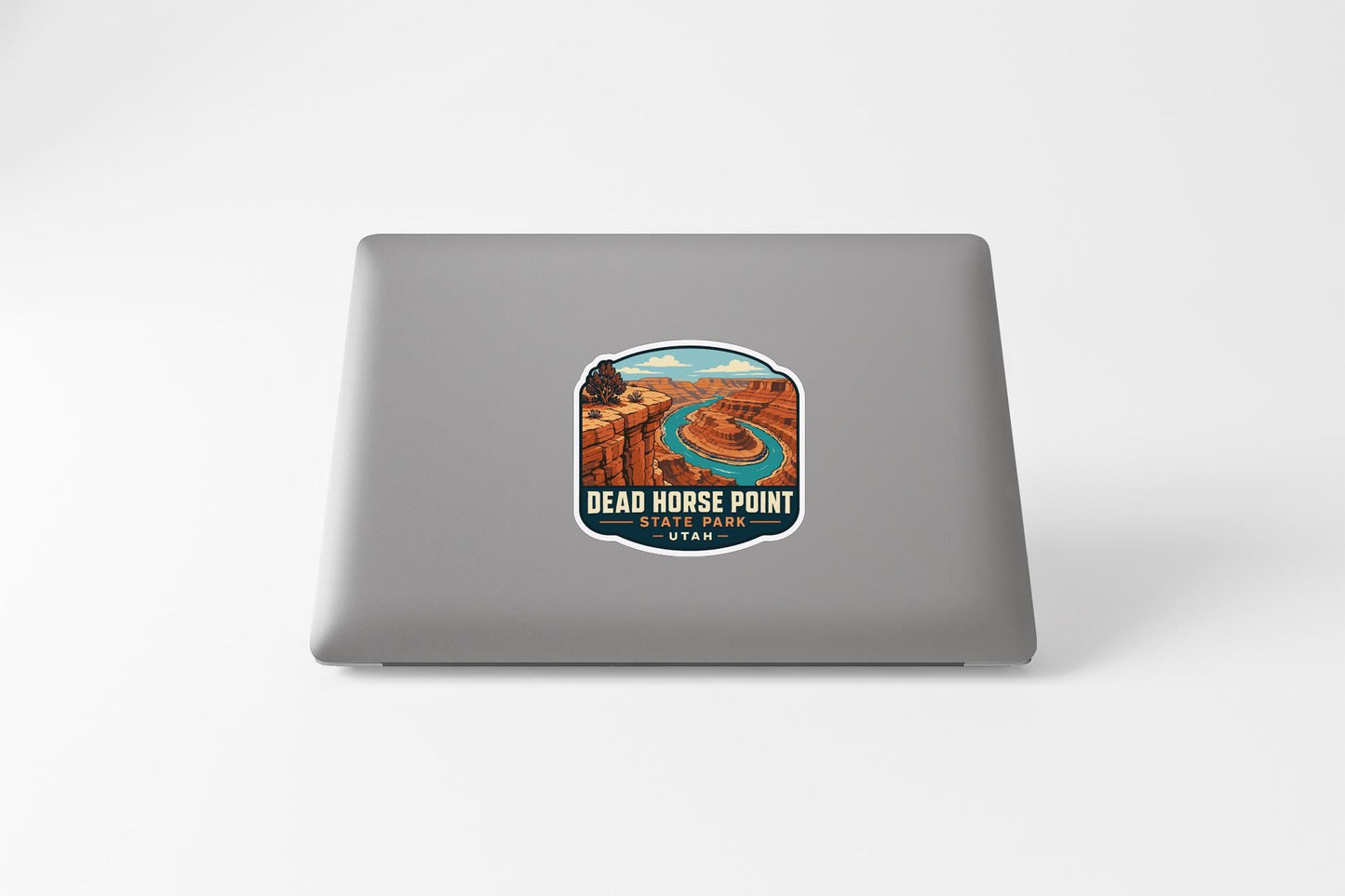 a sticker on the back of a laptop, depicting a scenic landscape with a river and mountains.