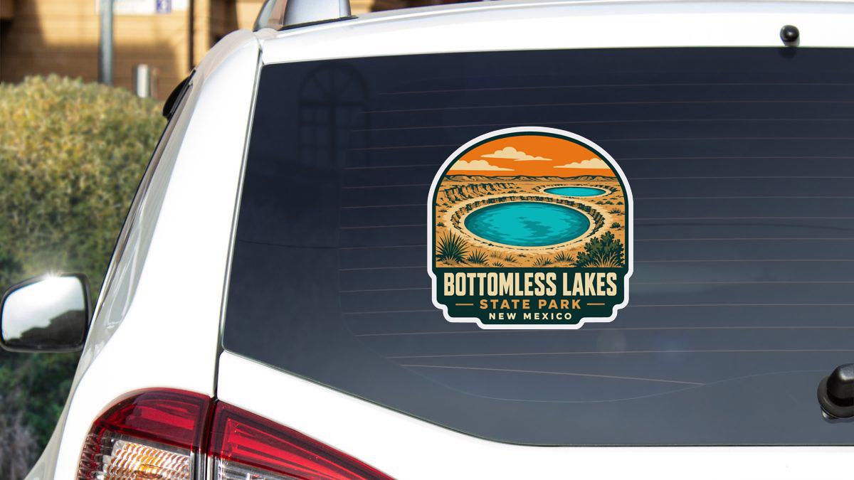 A sticker on the rear window of a white car, depicting a scenic landscape with a lake and mountains.