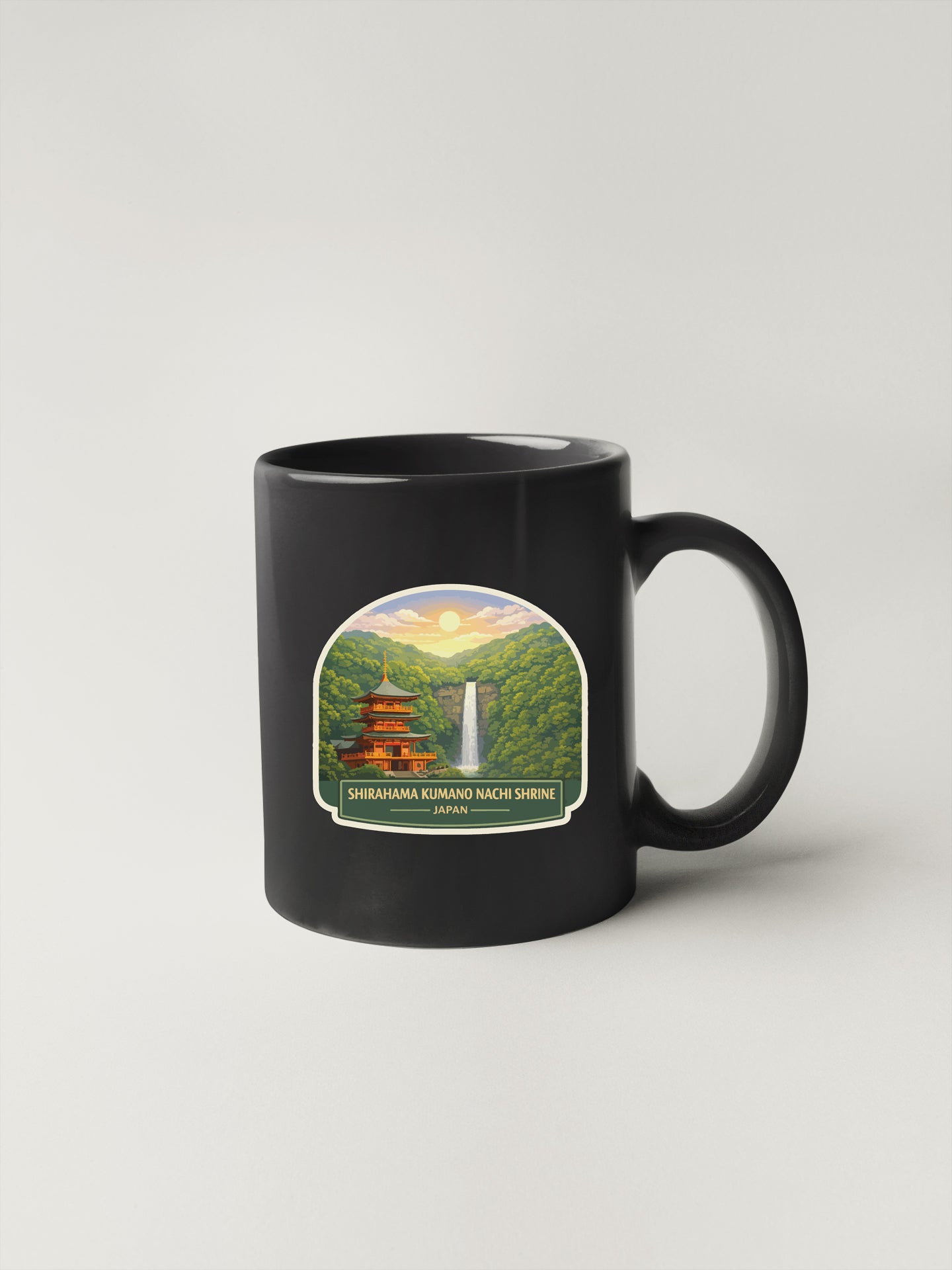 A black coffee mug with a label depicting a scenic landscape featuring a waterfall and a temple.