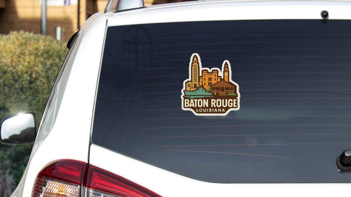 A sticker on the rear window of a white car, depicting the city of Baton Rouge, Louisiana.