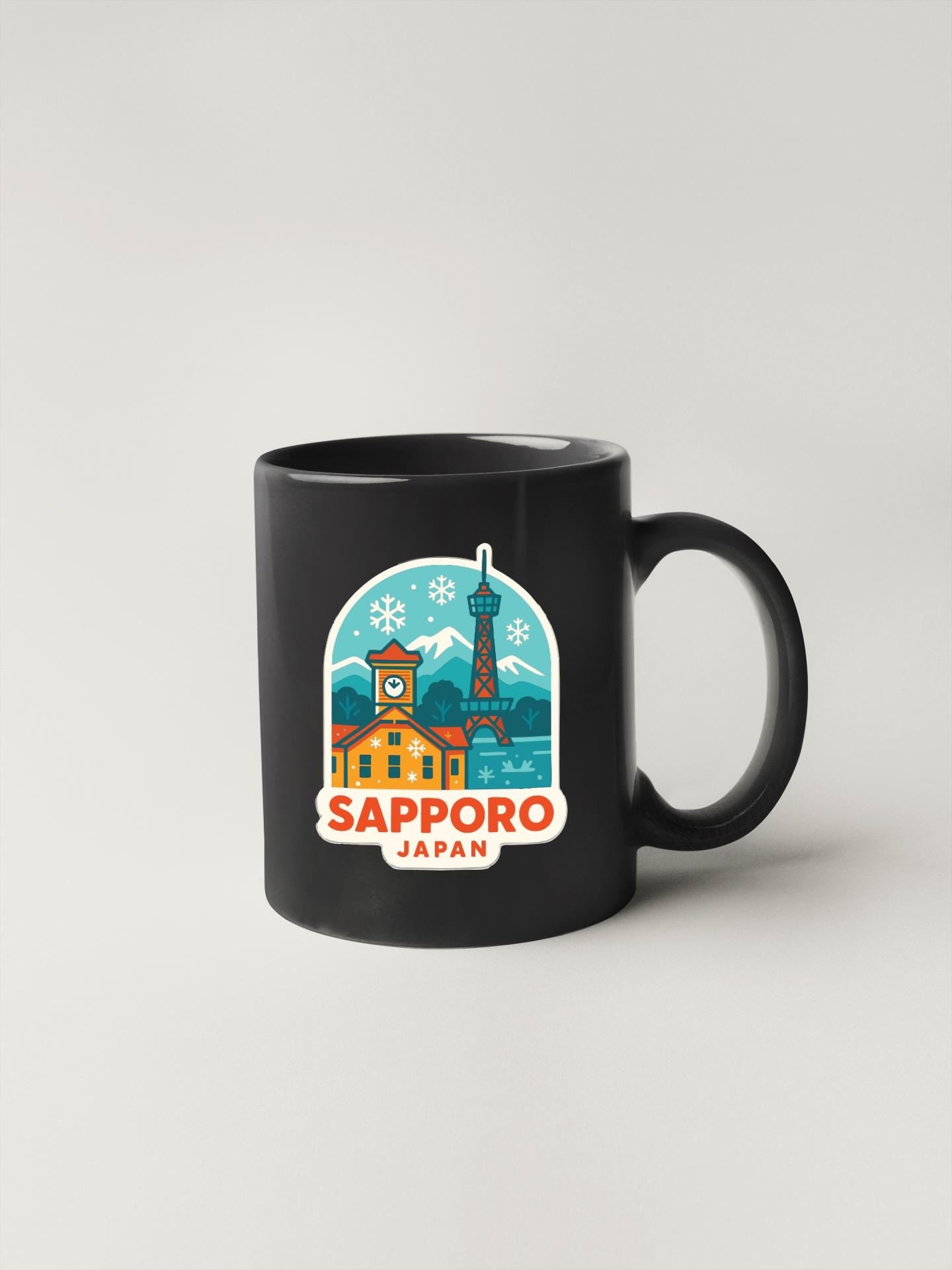 A black coffee mug with a colorful illustration of Sapporo, Japan, featuring a clock tower, a building, and snowflakes.