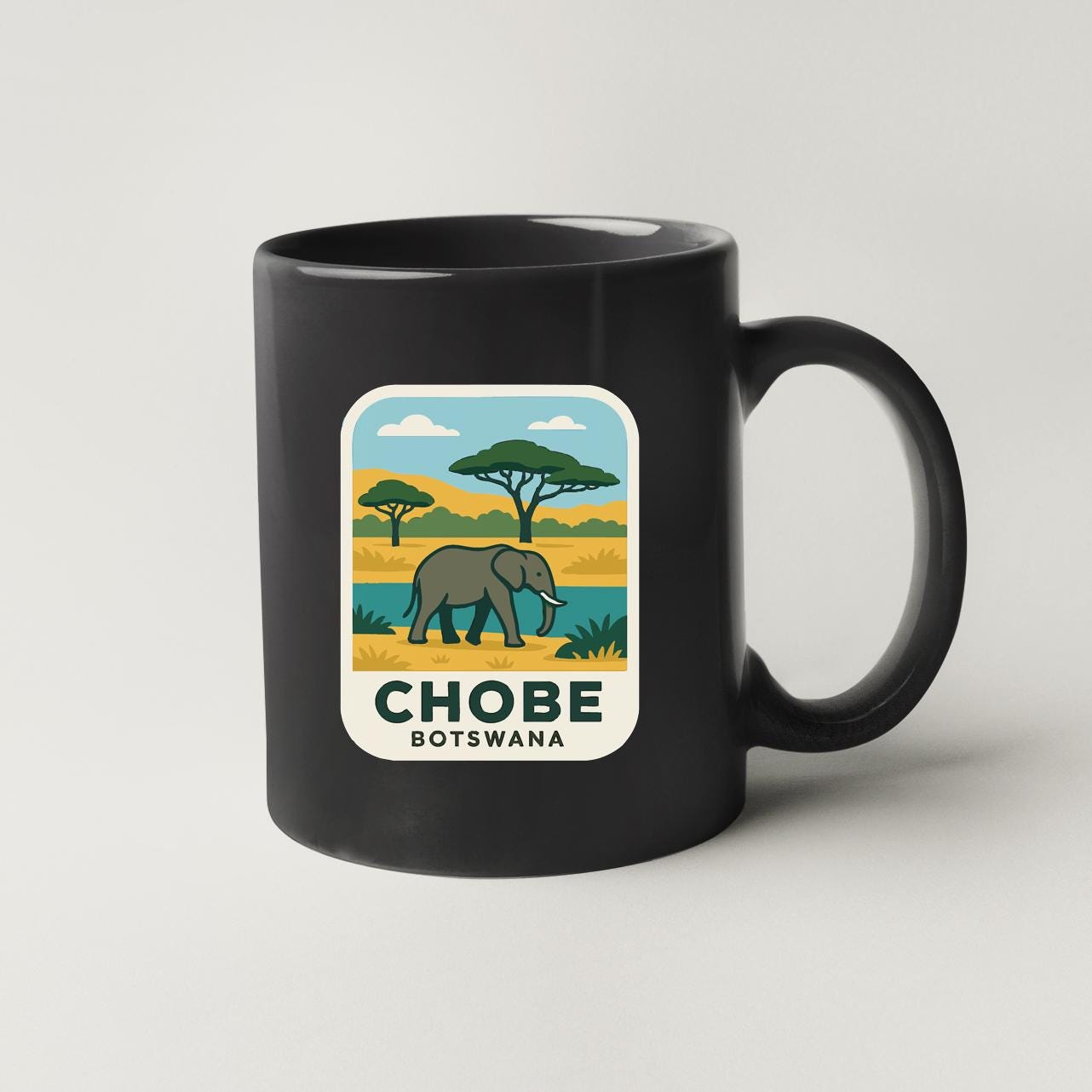A black coffee mug with a graphic design depicting an elephant in a savanna landscape, along with the text "CHOBE BOTSWANA".